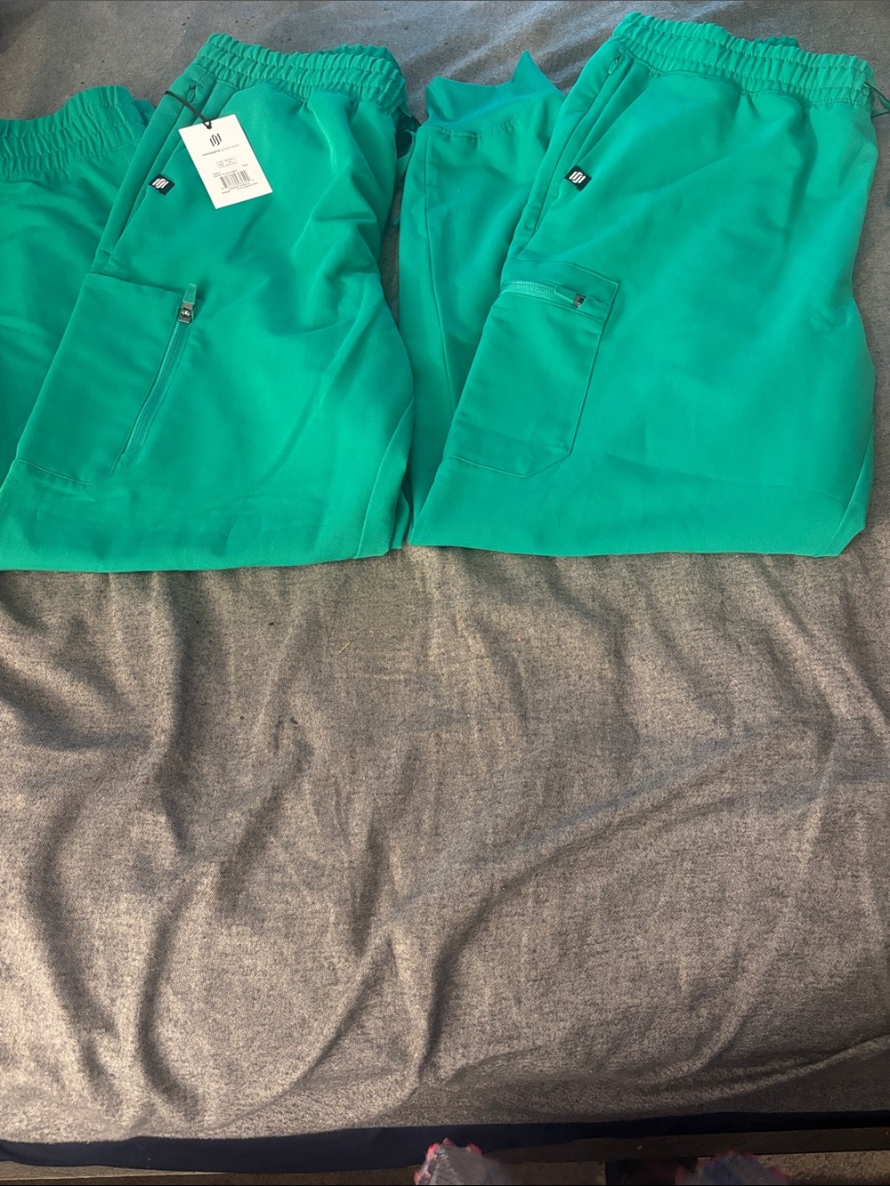 Two Pairs of Jaanuu Emerald Green Scrub Jogger Pants with Pocket Details.